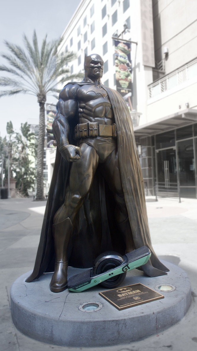 The actual green Onewheel GT photographed beside the Batman statue in Burbank
