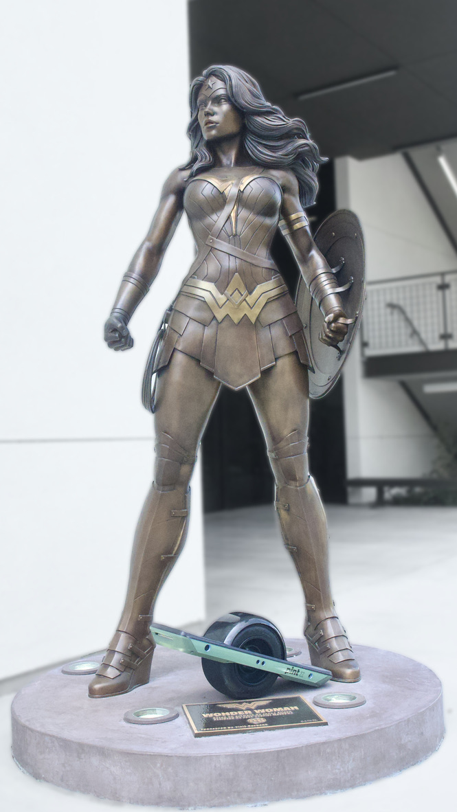 The actual green Onewheel Pint X photographed with the Wonder Woman statue